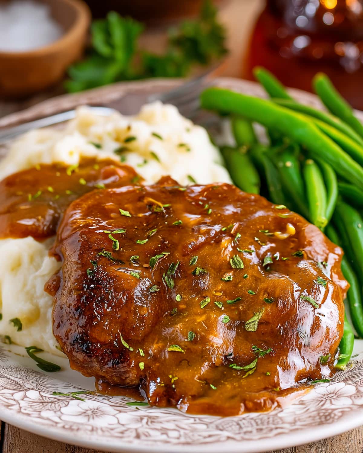 Crock Pot bucket steak covered in rich brown gravy, served with creamy mashed potatoes and fresh green beans.