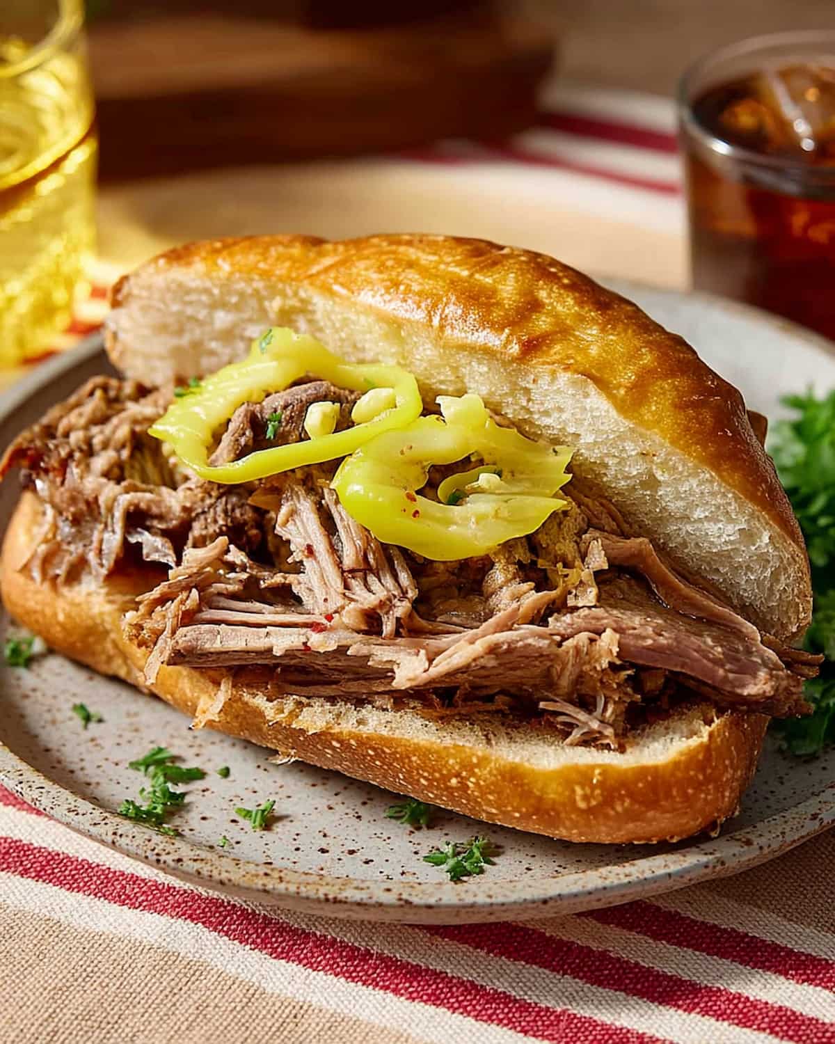 Crock Pot Italian beef sandwiches on a toasted bun, filled with tender shredded beef and tangy pepperoncini slices.