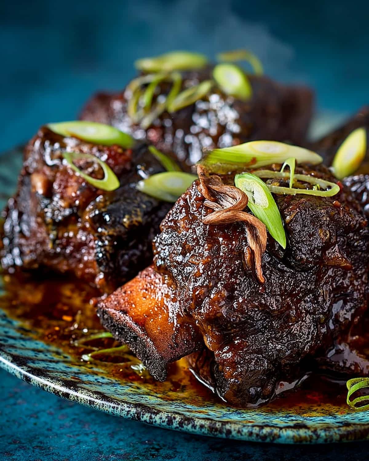 Slow Cooker Korean short ribs glazed in rich sauce and garnished with sliced green onions for a savory, flavorful meal.