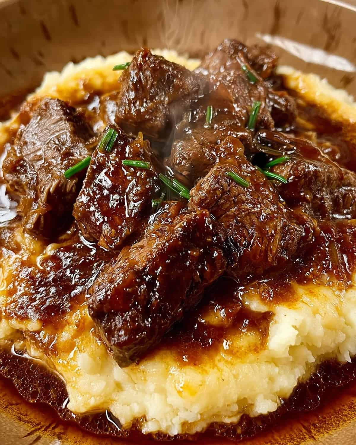 Tender beef over creamy mashed potatoes smothered in rich crock pot brown gravy.