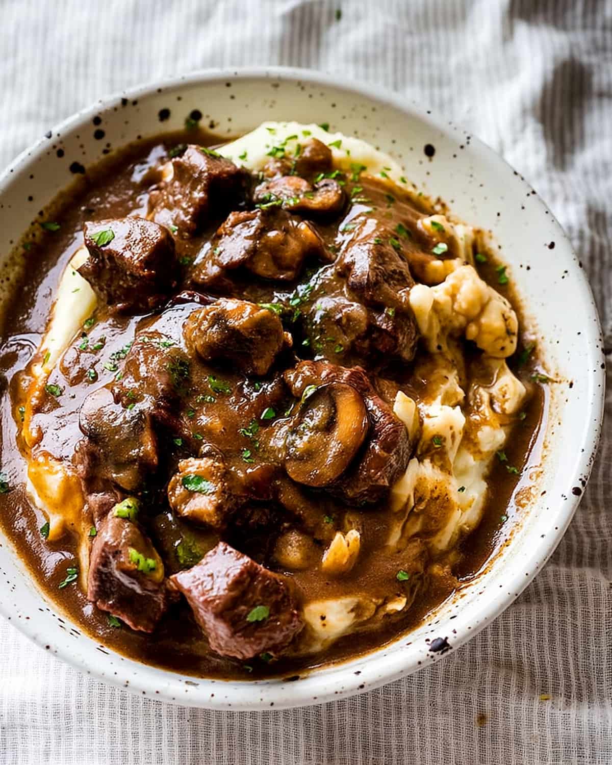 Crock Pot beef tips with mushroom gravy served over creamy mashed potatoes, rich brown sauce