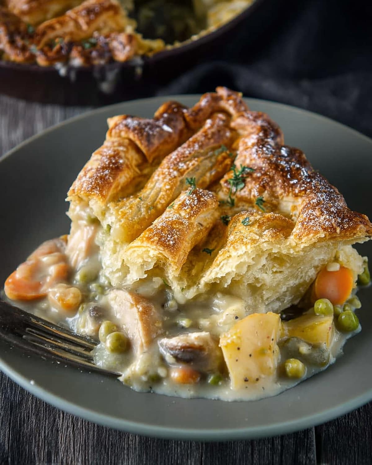 Slow Cooker vegetable pot pie with flaky golden crust, creamy vegetable filling, and tender potatoes, peas, and carrots on a plate.