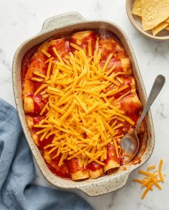 Crock-Pot Red Chicken Enchiladas in a baking dish with red sauce and bubbly melted cheese on top