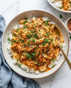 Easy Crockpot Cajun Butter Chicken over fluffy rice with creamy Cajun butter sauce and parsley, close-up in a bowl