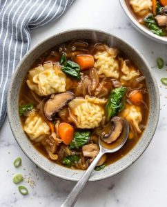 Bowl of Slow Cooker Potsticker Soup with tender dumplings, ginger-soy broth, cabbage, carrots, and green onions