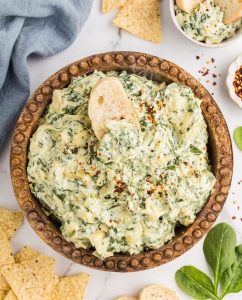 Creamy spinach artichoke dip crockpot style, hot and cheesy with bubbly edges, ready for dipping at a party